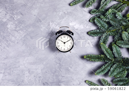 Black clock on grey concrete background with Christmas branches. 59061822