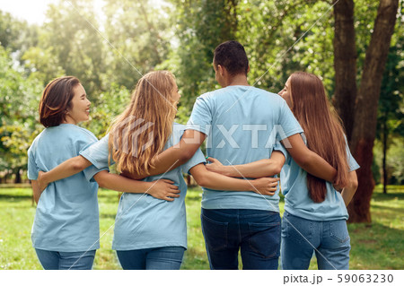 Volunteering. Young people volunteers outdoors walking hugging back view talking laughing cheerful Volunteering. Young people volunteers outdoors walking hugging back view talking laughing cheerful 59063230
