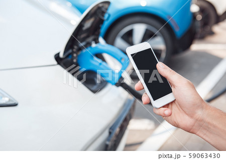 Young adult man using smartphone and paying for charging electric car Young adult man using smartphone and paying for charging electric car 59063430