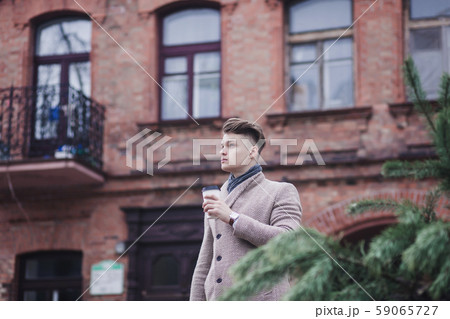 man standing outdoors holding coffee man standing outdoors holding coffee 59065727