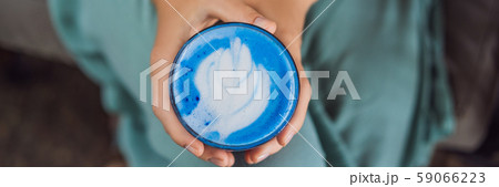 Young woman having a mediterranean breakfast seated at sofa and drinks Trendy drink: Blue latte. Hot Young woman having a mediterranean breakfast seated at sofa and drinks Trendy drink: Blue latte. Hot 59066223