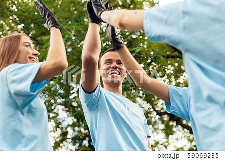 Volunteering. Young people volunteers outdoors standing together giving high five mission complete 59069235