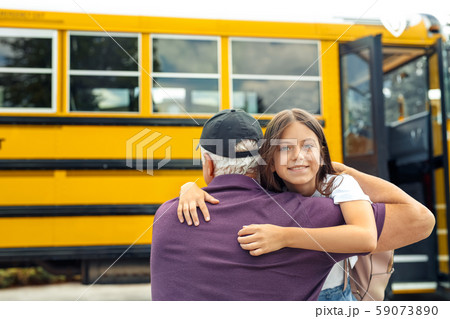 Father meeting daughter coming out of school bus hugging girl smiling playful blurred background Father meeting daughter coming out of school bus hugging girl smiling playful blurred background 59073890