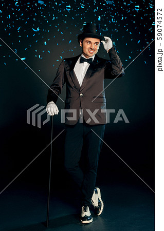 Professional Occupation. Showman in suit gloves and hat standing isolated on wall with cane posing Professional Occupation. Showman in suit gloves and hat standing isolated on wall with cane posing 59074572
