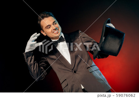 Professional Occupation. Showman in suit and gloves standing isolated on wall making tricks with hat Professional Occupation. Showman in suit and gloves standing isolated on wall making tricks with hat 59076062