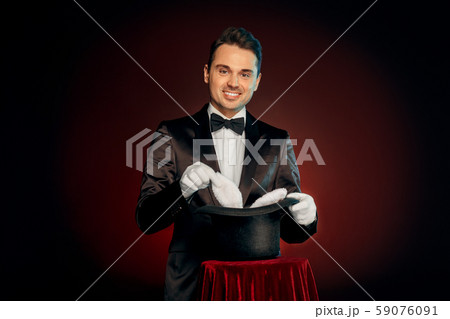 Professional Occupation. Magician in suit and gloves standing isolated on wall making trick taking 59076091