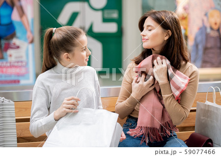 Pleased woman holding new cashmere scarf by chest while girl looking at mother 59077466