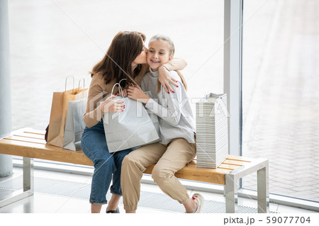 Young affectionate mother kissing her pretty daughter on cheek while resting Young affectionate mother kissing her pretty daughter on cheek while resting 59077704