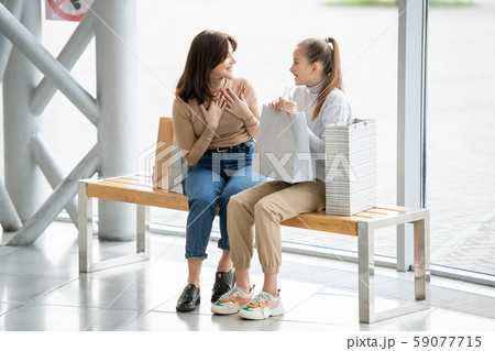 Cheerful females in casualwear discussing something curious while having rest Cheerful females in casualwear discussing something curious while having rest 59077715