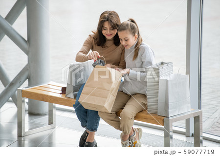 Happy female and her daughter opening paperbag and looking at what they bought 59077719
