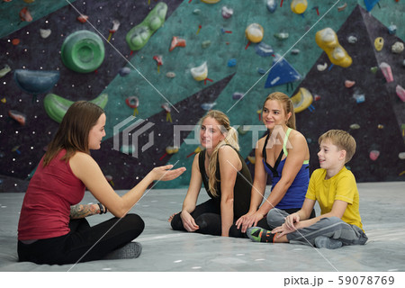 Climbing instructor with crossed legs sitting in front of three trainees Climbing instructor with crossed legs sitting in front of three trainees 59078769
