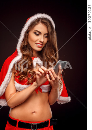 Christmas and New Year. Woman in santa costume with hood standing isolated on black browsing 59079188