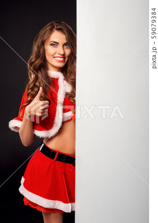Christmas and New Year. Woman in santa costume standing isolated on black with white board showing Christmas and New Year. Woman in santa costume standing isolated on black with white board showing 59079384