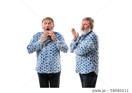 Senior man arguing with himself on white studio background. 59080311