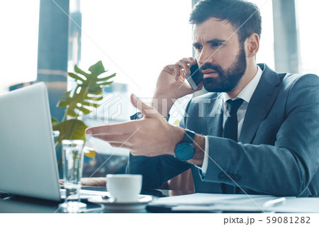 Businessman sitting in a business center restaurant smartphone communication unsatisfied Businessman sitting in a business center restaurant smartphone communication unsatisfied 59081282