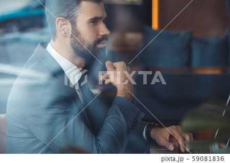 Businessman sitting in a business center restaurant with laptop thoughtful 59081836