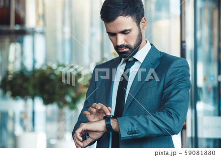 Businessman in a fromal suit in a business center checking time Businessman in a fromal suit in a business center checking time 59081880