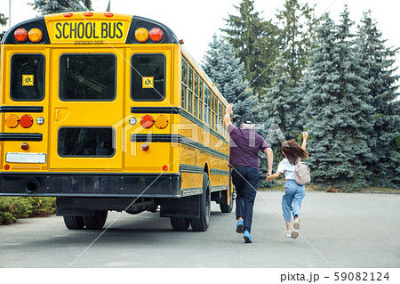 Being Late. Father and daughter following school bus back view waving to driver 59082124