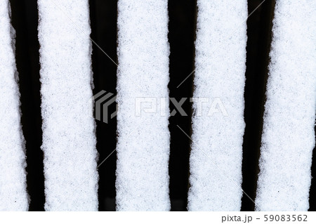 the first snow on bars of wooden bench outdoors 59083562