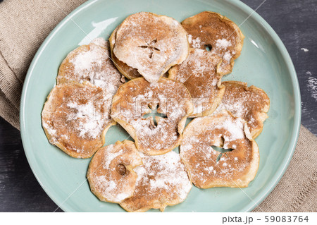 Round green plate with homemade  apple chips sprinkled with powdered sugar and cinnamon on burlap. Fruit healthy snack. Close-up, top view. 59083764