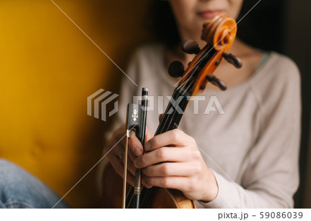 Beautiful girl posing with a violin in a soft chair 59086039