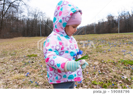 Little girl with spring snowdrop flowers in hand 59088796