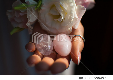 Female hands holding two yoni eggs for vumfit, imbuilding or meditation are made from pink quartz 59089711
