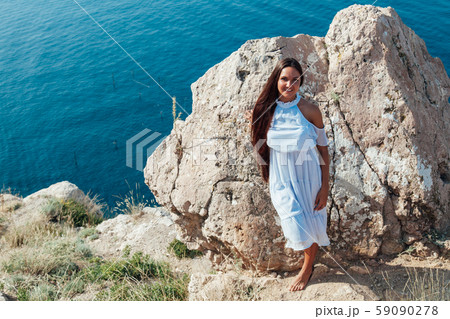 A beautiful woman with long hair in a dress looks at the landscape 59090278