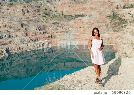 Beautiful woman with long hair in dress looks at the landscape of the lake Beautiful woman with long hair in dress looks at the landscape of the lake 59090320
