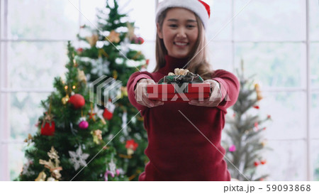 Asian girl giving Christmas present to camera, with smiling face Asian girl giving Christmas present to camera, with smiling face 59093868
