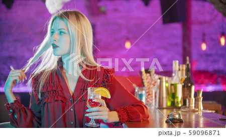 Gorgeous blonde young woman with red lipstick sitting by the bartender stand and playing with her Gorgeous blonde young woman with red lipstick sitting by the bartender stand and playing with her 59096871