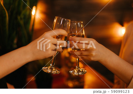 Close-up of two glasses of Champagne clinking together on festive background Close-up of two glasses of Champagne clinking together on festive background 59099123