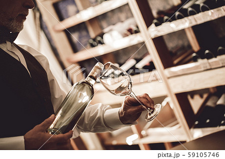 Sommelier Concept. Senior man standing pouring white wine into glass concentrated close-up 59105746