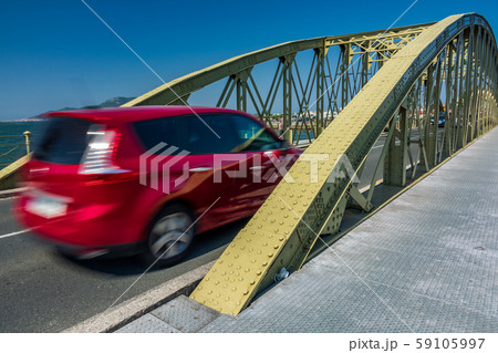 Blurred red car entering vintage iron bridge 59105997