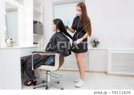 The master hairdresser blows the client's hair with a hairdryer, keratin recovery. hair care concept 59111626