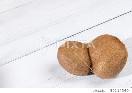 One non-standard deformed conjoined ugly kiwi on diagonal white painted wooden table. Top view, copy space. Waste zero concept. Image with copy space. One non-standard deformed conjoined ugly kiwi on diagonal white painted wooden table. Top view, copy space. Waste zero concept. Image with copy space. 59114540