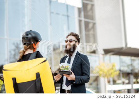 Female courier delivering food to an office worker 59115324