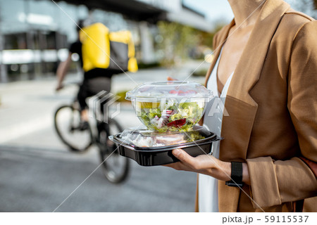 Courier delivering food to a business woman Courier delivering food to a business woman 59115537