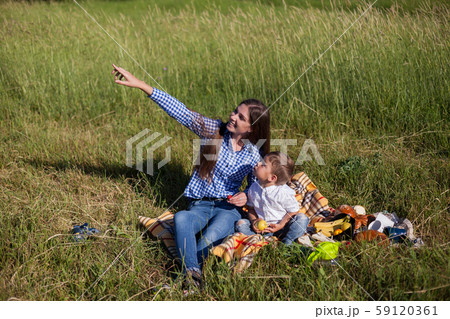 beautiful woman with her son on a picnic in a field near the forest beautiful woman with her son on a picnic in a field near the forest 59120361