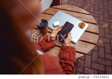 Young female looking at her phone in a street cafe 59124601