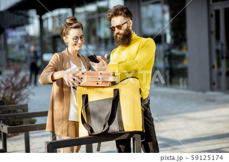 Man delivering pizza to a young woman client 59125174