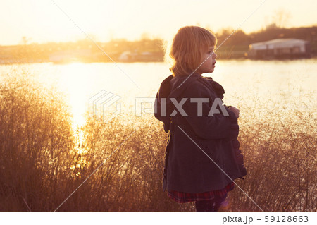 Little girl standing on river bank, on autumn Little girl standing on river bank, on autumn 59128663