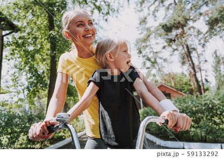 Beautiful smiling woman riding bike with her daughter Beautiful smiling woman riding bike with her daughter 59133292