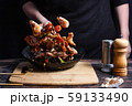 Chef at work. Hand holds a hot pan with fried shrimp and vegetables in sweet and sour sauce. Process of preparation of shrimps over dark background 59133490