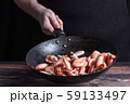 Chef at work. Hand holds a hot pan with fried shrimp. Process of preparation of shrimps over dark background 59133497