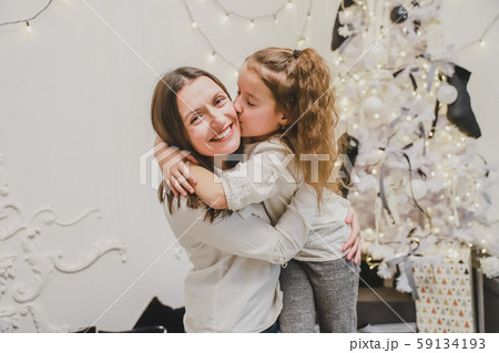 Cheerful mother and daughter near beautiful decorated Christmas tree, cuddling. Cheerful mother and daughter near beautiful decorated Christmas tree, cuddling. 59134193