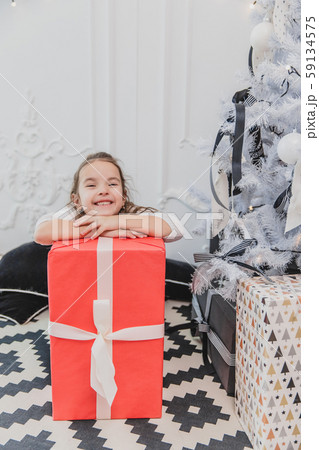 Careless, smiling small female enjoying Christmas time and presents. 59134575