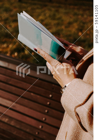 Woman in an autumn coat holds a book. Autumn park 59141105