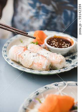 Man eating rice paper summer rolls with 59142394