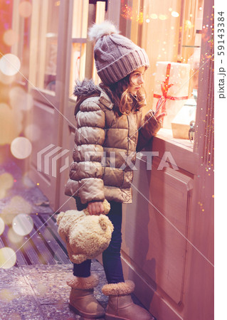 Little girl in front of window of a store, full of wrapped gifts; Christmas background Little girl in front of window of a store, full of wrapped gifts; Christmas background 59143384